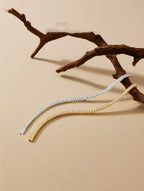 Own Your Bloom Radiant Rhythm Tennis Bracelet gold and silver edition displayed on beige background with organic wood accent, Dallas.