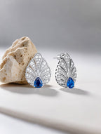 Own Your Bloom Brilliant Gleam sapphire diamond earrings resting on textured surface, symbolizing modern grace and timeless luxury, Boston.