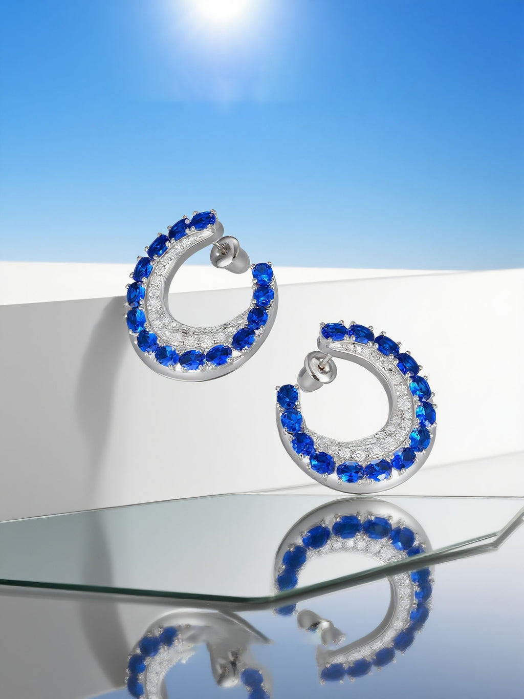 Own Your Bloom sapphire hoop earrings arranged on reflective surface with modern daylight aesthetic, Boston.