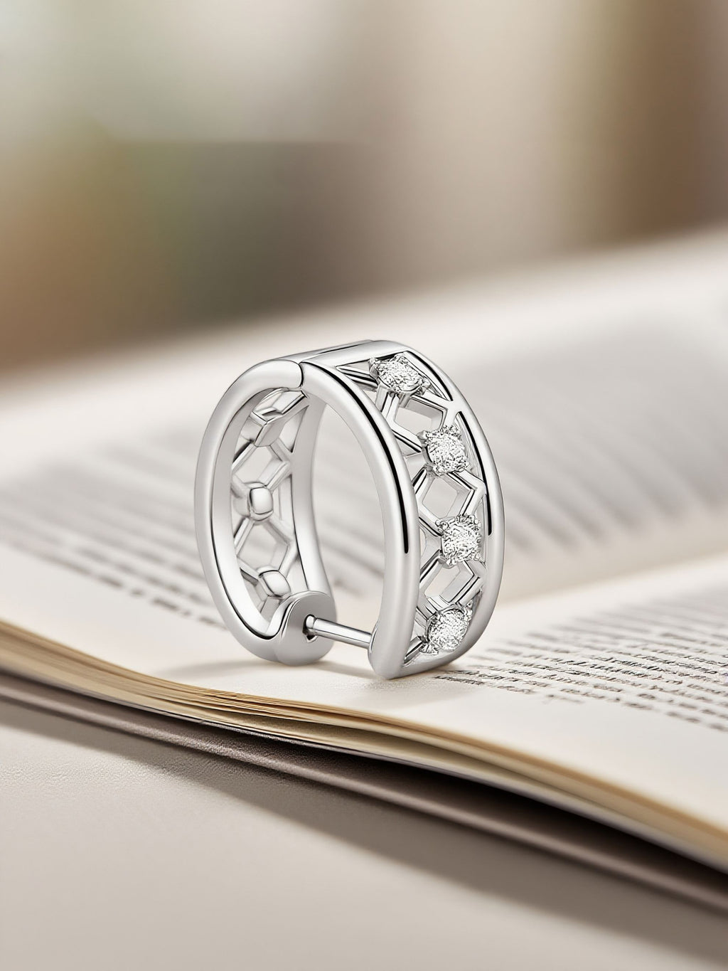 Own Your Bloom silver lattice geometric earrings displayed on book pages under soft sunlight, refined modern jewelry, Miami.