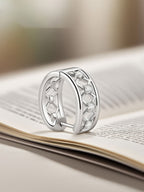 Own Your Bloom silver lattice geometric earrings displayed on book pages under soft sunlight, refined modern jewelry, Miami.