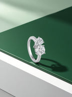 Own Your Bloom two stone Toi et Moi ring displayed on green and white pedestal, modern fine jewelry photography, Miami.