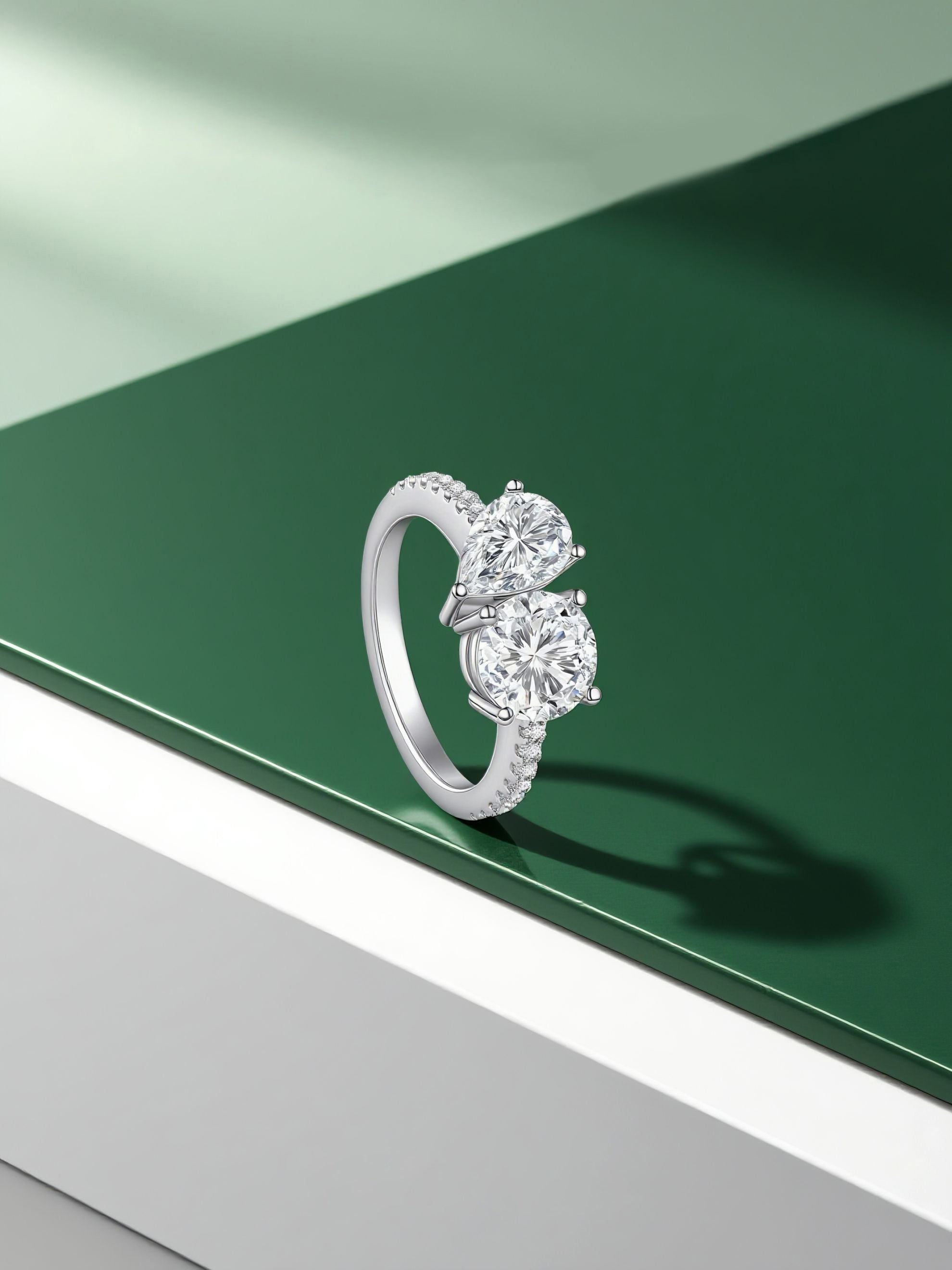 Own Your Bloom two stone Toi et Moi ring displayed on green and white pedestal, modern fine jewelry photography, Miami.
