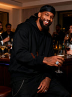 Lifestyle bar-scene shot of Own Your Bloom wide-band pavé ring in white-gold-plated finish.